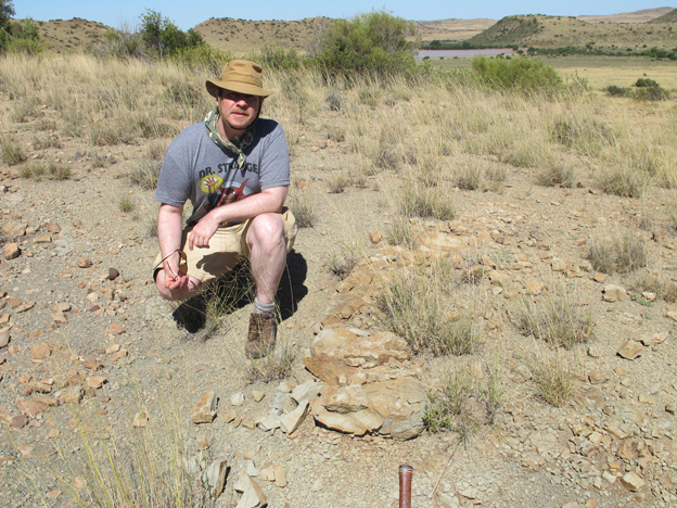 Dr. Sean Modesto conducting research in the field in South Africa, standing next to a burrow cast.