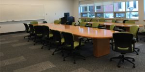 boardroom with large table and green chairs white walls large windows