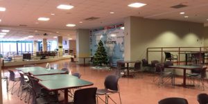 cafeteria on campus with green rectangle tables and black chairs