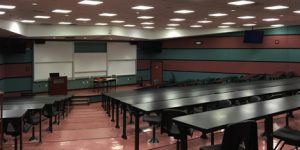 lecture theatre with stepped sitting and black color benches with green and red striped walls and large whiteboards