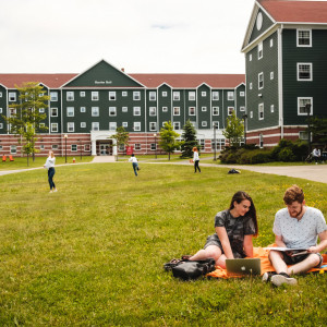 Students sitting in CBU courtyard near residence buildings.