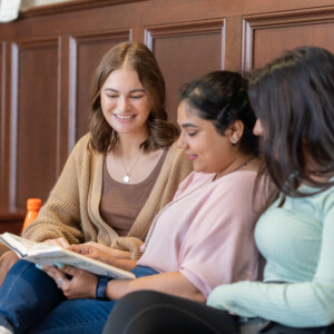Three girls reading book and talking with each other