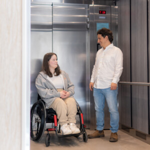 A man talking with a girl with wheelchair near elevator